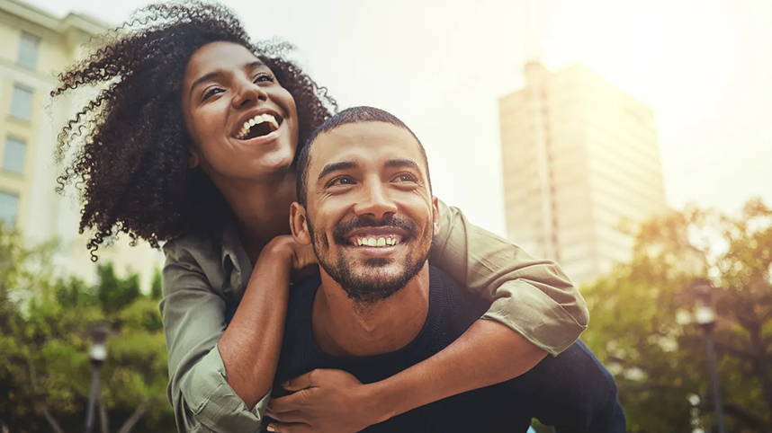Two people smiling, one on the others back