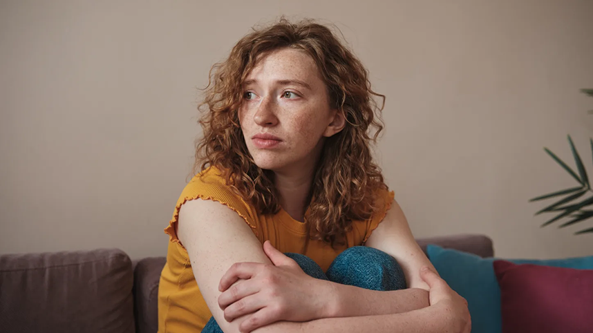 Person looking worried or sad with arms crossed sitting on sofa