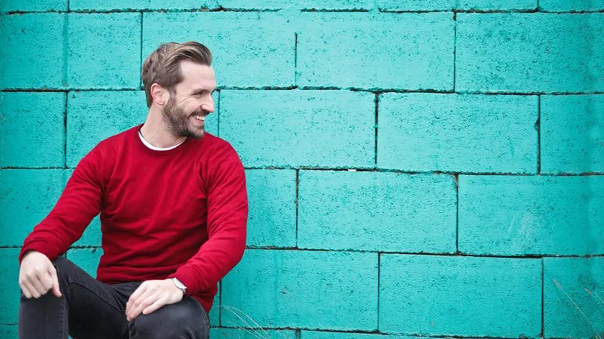 Smiling person leaning against green wall