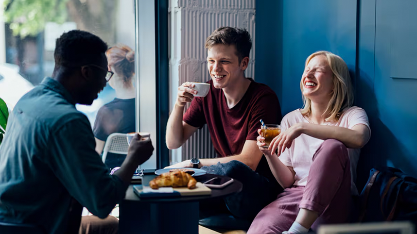 Group of smiling people sitting and drinking at a coffee shop