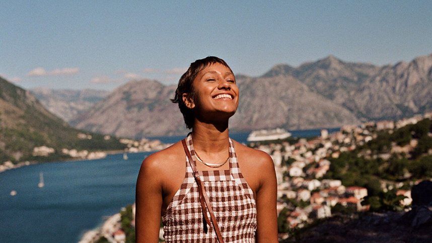 Smiling person with eyes closed above a coastlinea