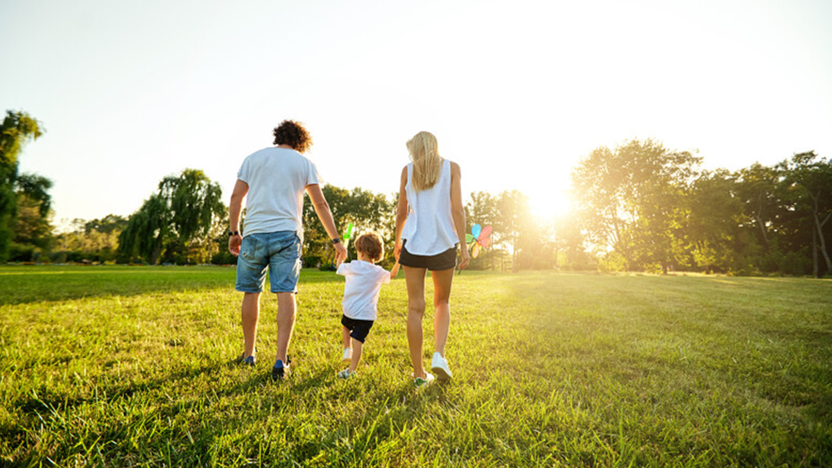 Couple walking holding hands with child in a park