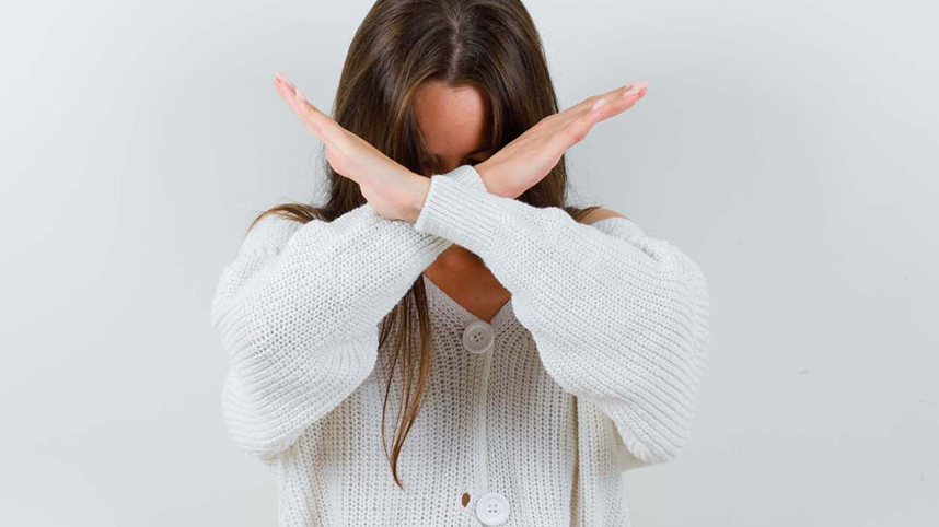 Person with their arms crossed in front of their face