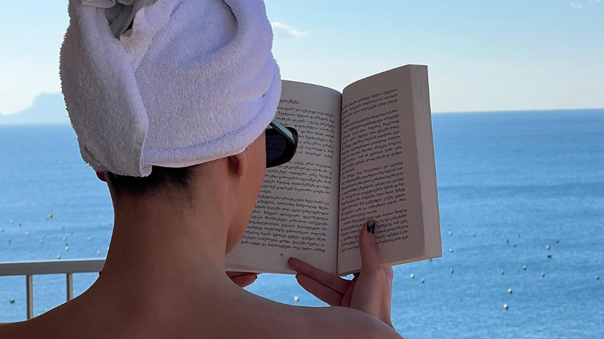 Person reading book in front of ocean