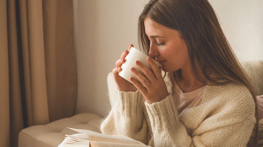 Person reading, drinking from mug