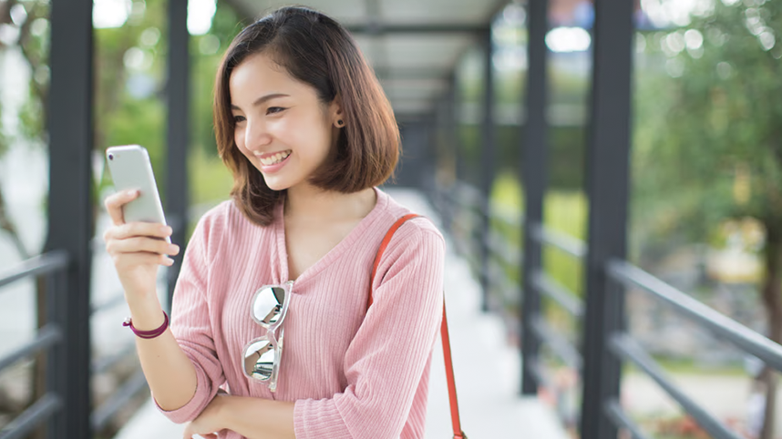 Person, outdoors, looking at phone smiling