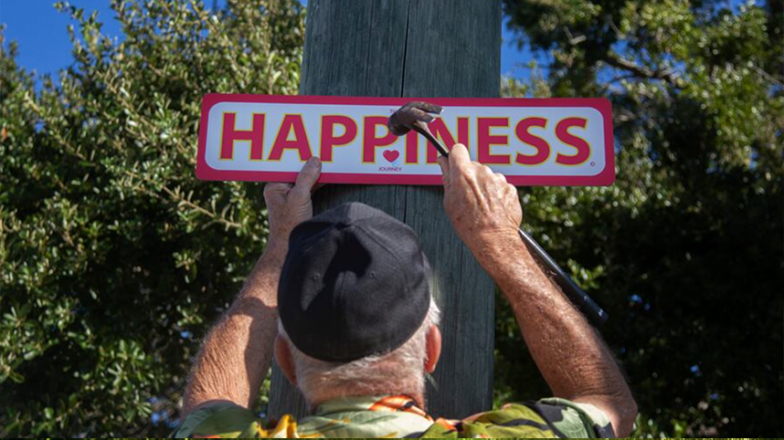 Person puts up sign saying "HAPPINESS"