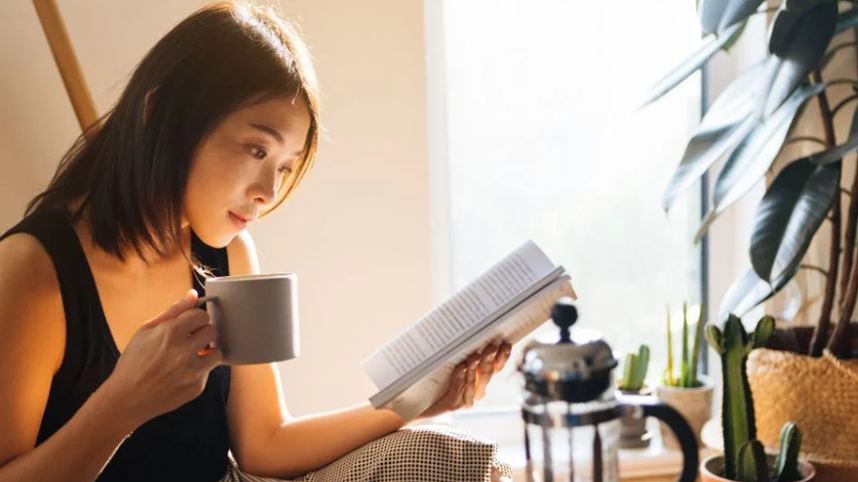 Woman reading book with a mug