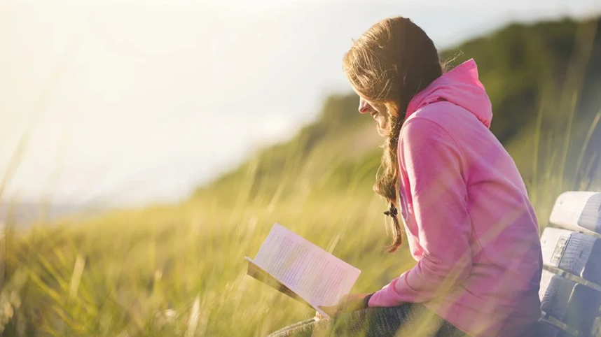 Person sitting and reading on hillside bench
